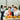 Smiling colleagues holding wrapped presents around a table with party food at an office Christmas celebration.
