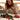 Concerned woman on the phone beside roses and a red heart-shaped gift box on a kitchen counter.
